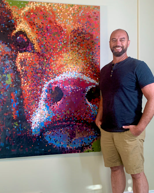 Brandon Bouck artist with a painting of a cow